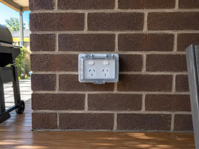Outdoor double power point with weatherproof cover on a brick exterior wall in Point Frederick